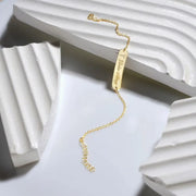 14k Gold filled bracelet with engraved bar tag on a white textured surface